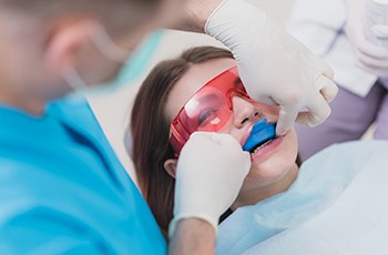 Dentist applying fluoride treatment on smiling patient's teeth