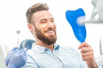 Man in dental chair looking at smile in mirror after ClearCorrect treatment