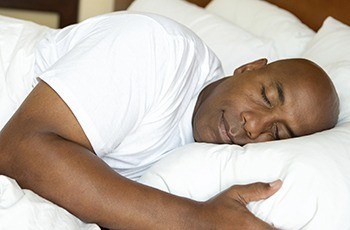 Man sleeping soundly in bed thanks to sleep apnea therapy
