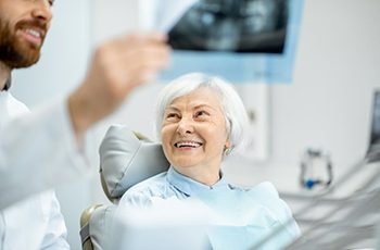 an older patient smiling at her dentist