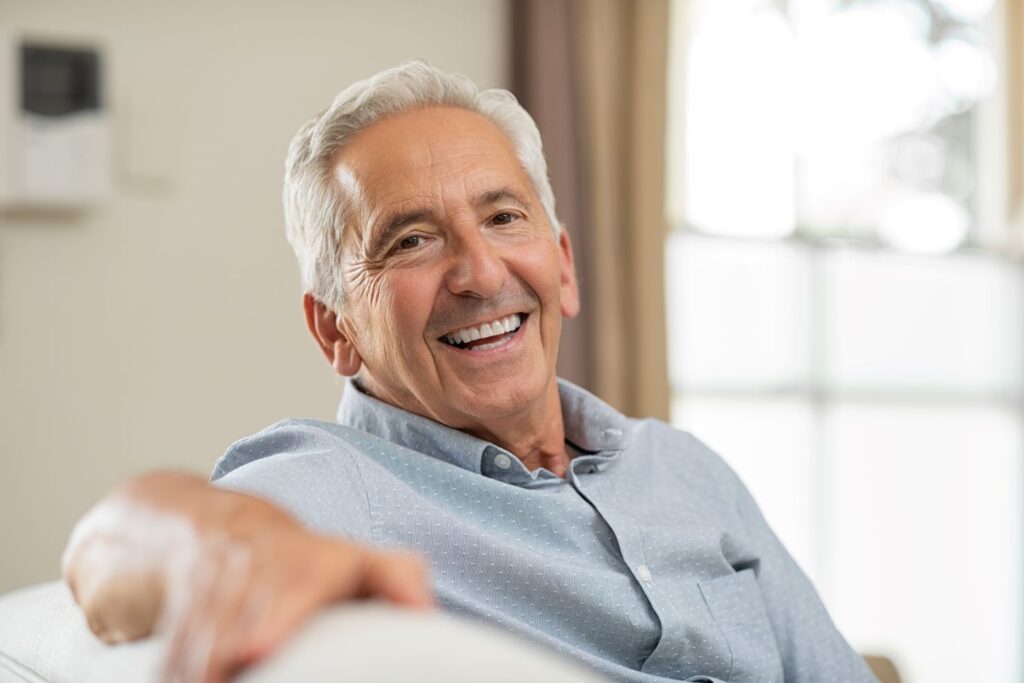 A smiling older man sitting on a couch