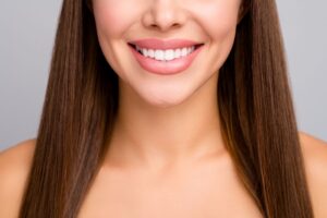 Nose-to-shoulder frontal view of a woman with long brown hair smiling