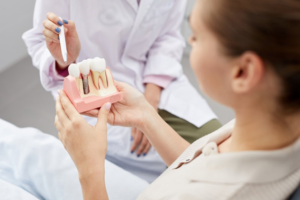 Top-down view of dentist and patient reviewing dental implant model