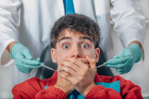 Close up of man covering his mouth so dentist can’t examine him